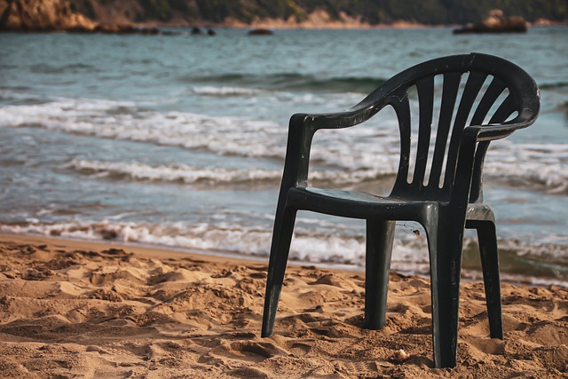 empty plastic chair on sand by ocean