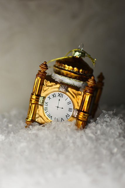 brass clock lying diagonally in icy snow; brass clock atop icy snow highlighting winter holiday season as a time of reflection and rejoicing